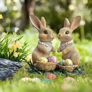 Detail of cute rabbit garden statues with mini baskets and colorful Easter eggs