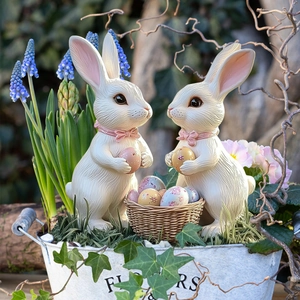Detail of resin Easter bunny figurines with painted eggs in a rustic garden flower bucket