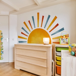 Detailed view of watercolor sun wall decal with colorful rays in a warm kids room setting