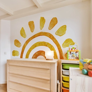 Detailed view of large watercolor sun wall decal in a cozy nursery room setting