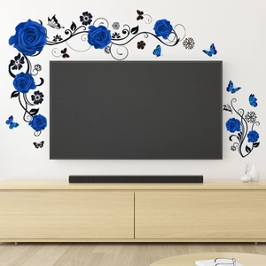 Dettaglio di adesivi murali rose blu e viti nere che circondano la TV in soggiorno