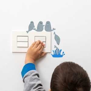 Detail view of cartoon seal switch wall decals showing blue water splash on white wall