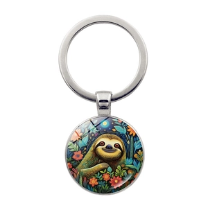 Detail of round glass cabochon keychain with a cute sloth and tropical floral illustration
