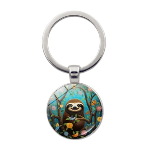 Detail of silver keyring featuring a round glass pendant with a cute sloth illustration