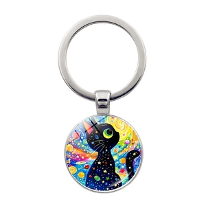 Dettaglio di un portachiavi in argento con illustrazione di gatto nero e cielo stellato