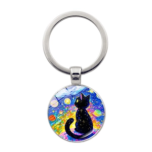 Dettaglio ravvicinato di un portachiavi in vetro con gatto nero e cielo stellato colorato