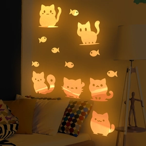 Luminous cartoon cat and fish wall stickers glowing orange in a cozy kids bedroom