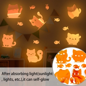 Detailed view of cat and fish wall stickers glowing in bright orange in a dark room