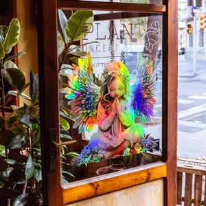 Iridescent angel girl window decal with rainbow gradient wings on a glass storefront