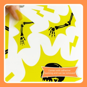 Halloween skull and lightning wall sticker with adhesive backing being peeled for application