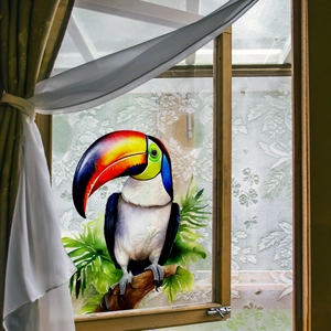 Vibrant watercolor toucan window sticker with tropical leaves on clear glass