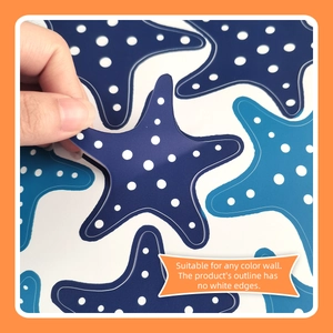 Close-up showing hand peeling blue starfish wall sticker with white polka dots