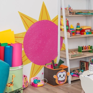 Vibrant sun wall decal and cartoon animal storage bins in a bright playroom setting