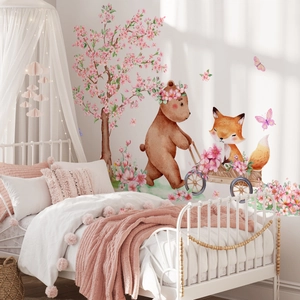 Nursery wall decals with a bear, fox, and blossom tree over a child's bed in a cozy room