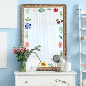 Close-up of floral watercolor mirror stickers applied on a gold-framed floor mirror
