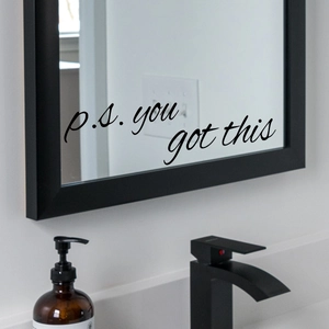 Detail showing 'p.s. you got this' vinyl sticker on a modern bathroom mirror surface