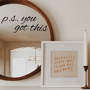 Detail of square framed wall art with orange inspirational quotes on a beige background