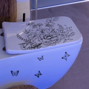 Black floral line art decals with butterflies on a white toilet cover in bathroom