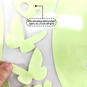 Peeling a green glow-in-the-dark butterfly wall sticker showing its self-adhesive backing