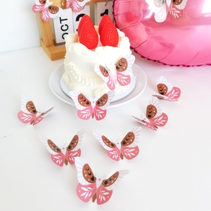Pink butterfly cake toppers with stars and moon patterns on a strawberry cream cake