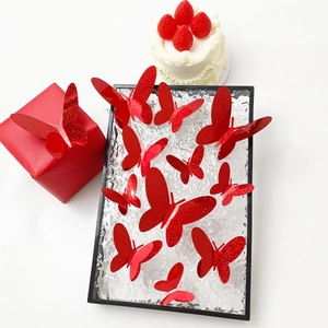 Detalle de pegatinas de mariposas 3D rojas con purpurina en caja de regalo y pastel festivo