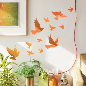 Macro detail of orange mirror acrylic wall stickers showing flying bird silhouettes