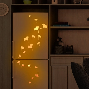 Luminous orange ginkgo leaf wall stickers glowing on a refrigerator in a cozy room