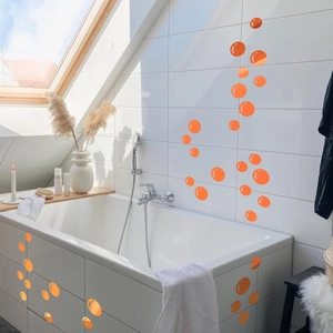Detailed view of orange bubble wall decals applied on bathroom tiles and bathtub