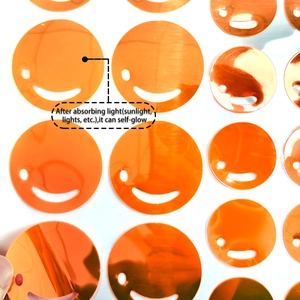 Close-up of orange glow-in-the-dark smiley face sequins for DIY bedroom wall decor