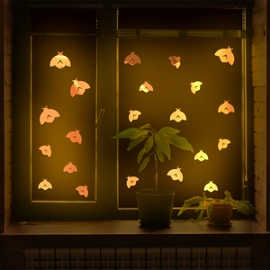 Detailed view of orange luminous moth window stickers glowing in dark room setting