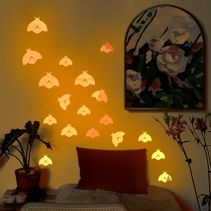 Luminous orange moth wall stickers glowing in warm light for bedroom decor