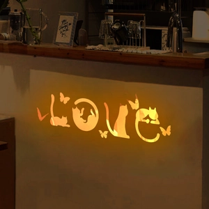Close-up of luminous cat-themed LOVE wall stickers with butterflies in a warm orange glow