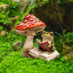 Garden frog reading on a book next to a red mushroom statue for outdoor decor