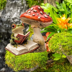 Macro detail of tropical frog reading a book under a red mushroom garden sculpture