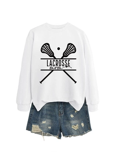 Flat lay of a white Lacrosse Mom sweatshirt and distressed blue denim shorts set