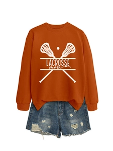 Flat lay of an orange Lacrosse Mom sweatshirt and blue distressed denim shorts on white