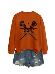 Flat lay of an orange Lacrosse Mom sweatshirt paired with ripped denim shorts