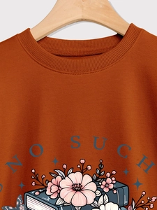 Close-up of caramel sweatshirt neckline with floral book illustration and blue lettering