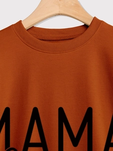 Close-up of ribbed crewneck and MAMA print on rust red long sleeve sweatshirt