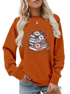 Close-up of orange sweatshirt showing book stack print and floral slogan detail