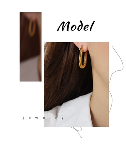 Detail view of gold U-shaped earrings with textured twill design worn by a model