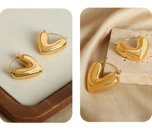 Makroaufnahme von 3D-Herz-Creolen in Gold auf elegantem Seiden- und Stein-Hintergrund