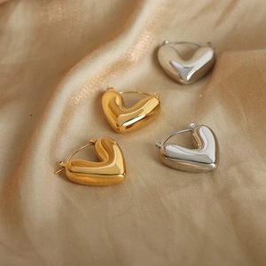 Minimalistische unregelmäßige Herz-Ohrringe in Gold und Silber auf Seidenstoff