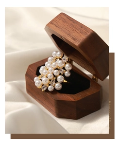 Macro shot of gold clustered pearl ring with zircons in a wooden jewelry box