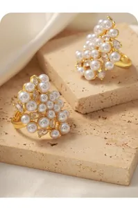 Detail of luxury irregular gold rings with clustered pearls and zircon on stone surface