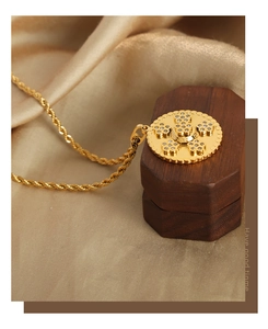 Détail du collier avec pendentif doré et motif floral en zircon sur fond de soie