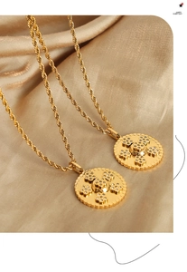 Gros plan d'un collier pendentif lotus doré sur un fond en soie couleur champagne