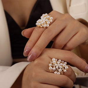 Elegant gold rings with clustered white pearls and marquise zircons worn by a model
