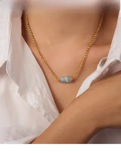 Primo piano della collana a catena dorata con ciondolo in pietra naturale blu su una modella
