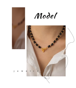 Detail of beaded black agate necklace with golden beads and OT toggle clasp on model